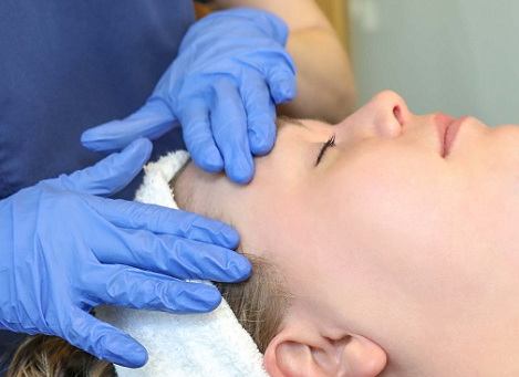 Doctor massaging a topical cream onto female patient's face